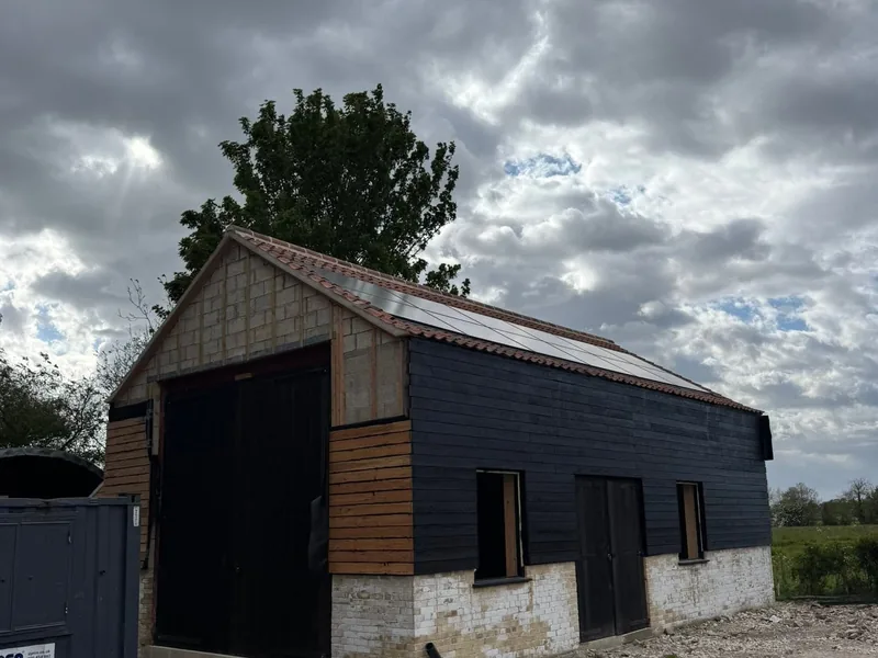 Outbuilding clad in black timber boarding with larch detail and a pantile roof