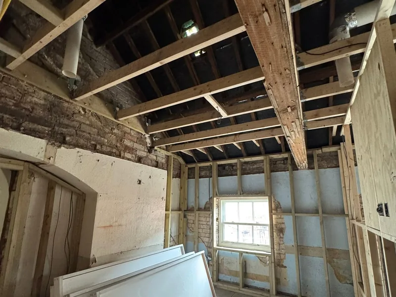 Stripped out room in an older building with exposed ceiling joists and new timber stud framing