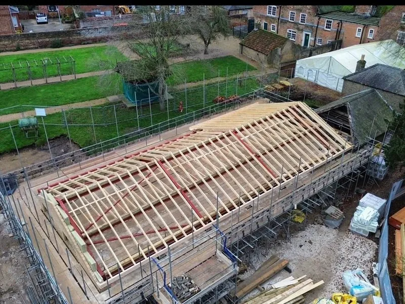 Elevated view of a new timber roof structure on a long building surrounded by scaffolding