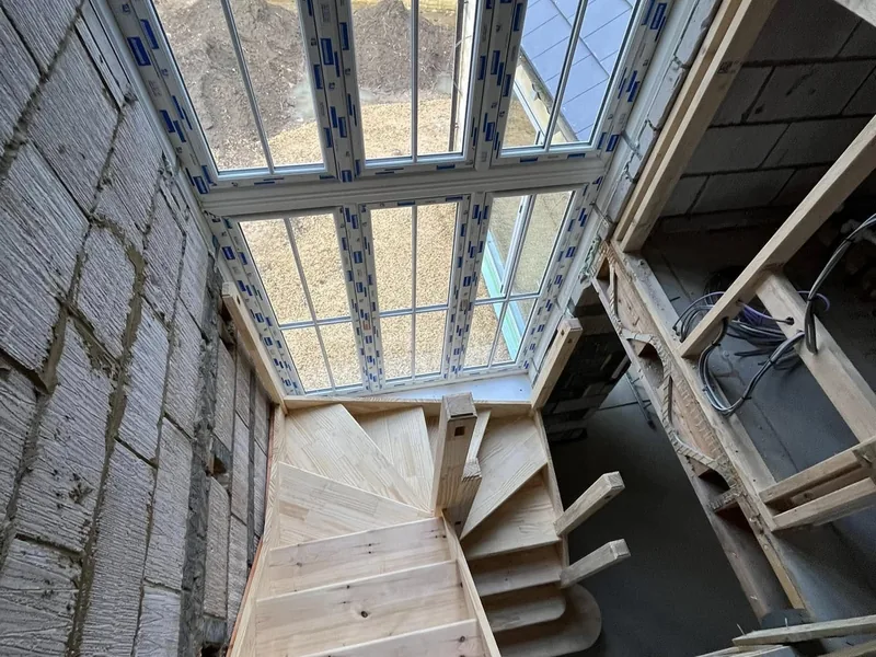 Softwood winder staircase seen from above in a blockwork shell below a large window