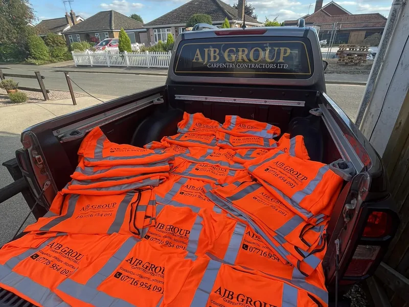 AJB Group branded pickup loaded with orange hi vis vests printed with the company name