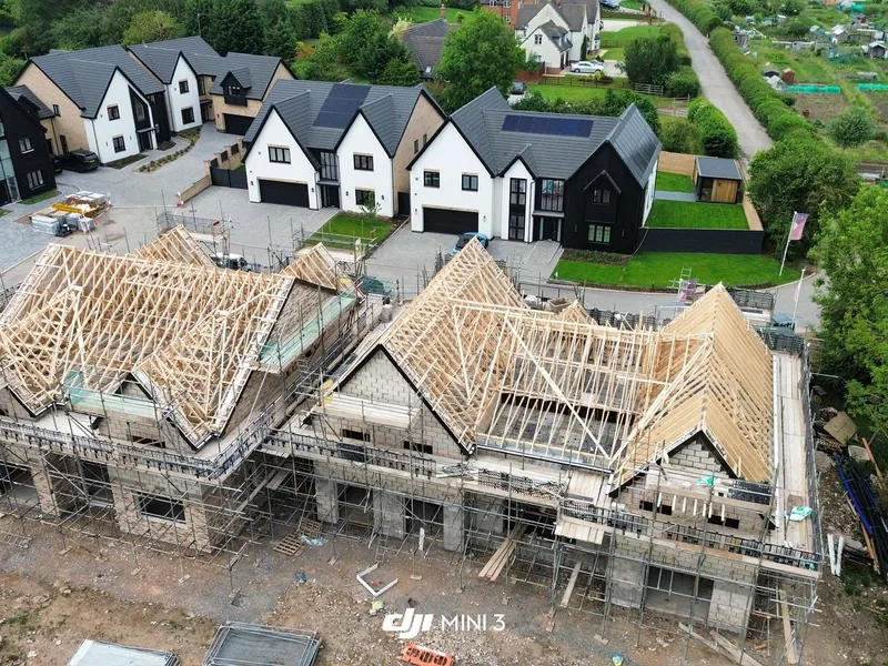 Aerial view of a housing development with timber roof trusses erected on scaffolded new homes